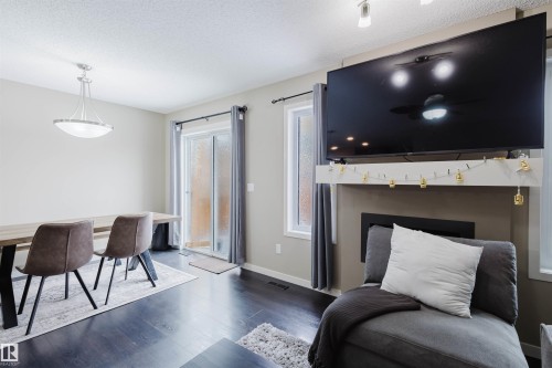 This living space features dark wood floors and light-colored walls - 16811 120 Street, Edmonton, AB - Indoor With Fireplace