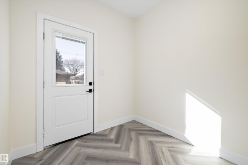 Entryway featuring a white door with a window, herringbone pattern flooring, and light-colored walls - 8319 81Ave, Edmonton, AB - Indoor Photo Showing Other Room