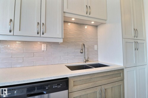 Kitchen with light stone counters, stainless steel dishwasher, and decorative backsplash - 304 11907 81 Street, Edmonton, AB - Indoor Photo Showing Kitchen With Double Sink With Upgraded Kitchen