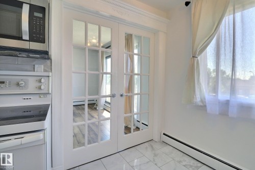 Doorway featuring french doors, baseboard heating, marble finish flooring, and a baseboard radiator - 304 11907 81 Street, Edmonton, AB - Indoor Photo Showing Other Room