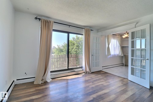 Unfurnished room with a textured ceiling, a baseboard heating unit, ceiling fan, a baseboard radiator, and wood finished floors - 304 11907 81 Street, Edmonton, AB - Indoor Photo Showing Other Room