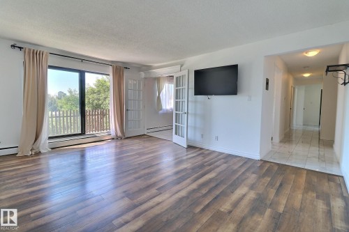 Unfurnished living room with light wood finished floors, a textured ceiling, and a baseboard heating unit - 304 11907 81 Street, Edmonton, AB - Indoor Photo Showing Living Room