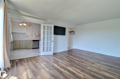 Unfurnished living room featuring light wood-style floors, a textured ceiling, ceiling fan, and french doors - 304 11907 81 Street, Edmonton, AB - Indoor