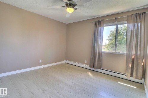 Unfurnished room featuring a baseboard radiator, light wood-style floors, a textured ceiling, and ceiling fan - 304 11907 81 Street, Edmonton, AB - Indoor Photo Showing Other Room