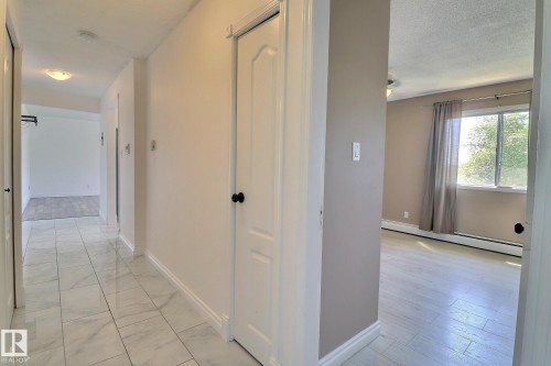 Hallway with a baseboard heating unit, light marble finish flooring, and a textured ceiling - 304 11907 81 Street, Edmonton, AB - Indoor Photo Showing Other Room
