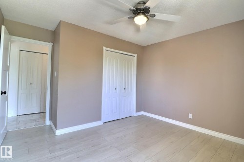 Unfurnished bedroom with a closet, ceiling fan, light wood-style floors, and a textured ceiling - 304 11907 81 Street, Edmonton, AB - Indoor Photo Showing Other Room