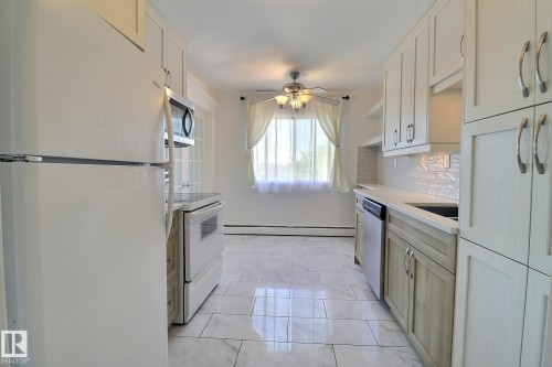 Kitchen featuring stainless steel appliances, a ceiling fan, decorative backsplash, baseboard heating, and open shelves - 304 11907 81 Street, Edmonton, AB - Indoor Photo Showing Kitchen With Upgraded Kitchen