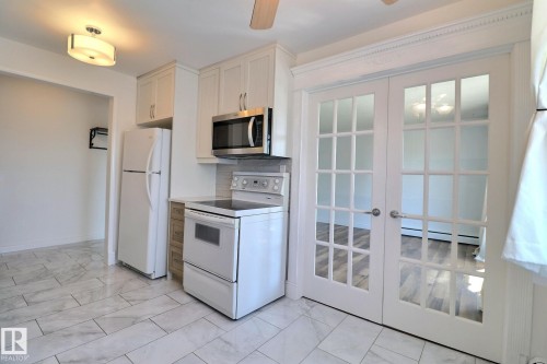 Kitchen with white appliances, ceiling fan, light countertops, backsplash, and white cabinets - 304 11907 81 Street, Edmonton, AB - Indoor Photo Showing Kitchen