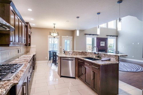 The kitchen features wood cabinetry, granite countertops, a gas cooktop, and a stainless steel dishwasher - 4016 Mactaggart Drive, Edmonton, AB - Indoor Photo Showing Kitchen With Upgraded Kitchen
