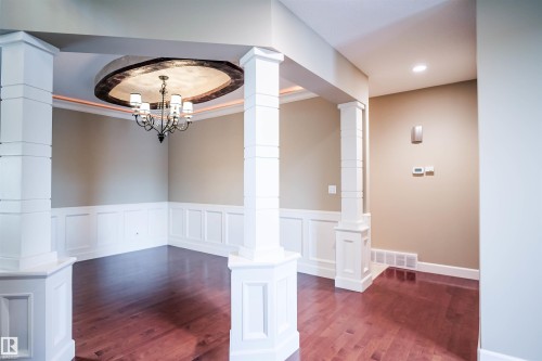 The interior of the property features rich hardwood flooring, decorative wainscoting, and accent pillars - 4016 Mactaggart Drive, Edmonton, AB - Indoor Photo Showing Other Room