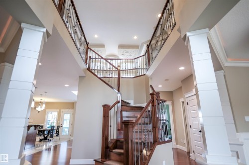 Grand entry featuring a multi-level staircase with dark wood handrails and wrought iron balusters, recessed lighting, and a view of the main living area with hardwood floors - 4016 Mactaggart Drive, Edmonton, AB - Indoor Photo Showing Other Room