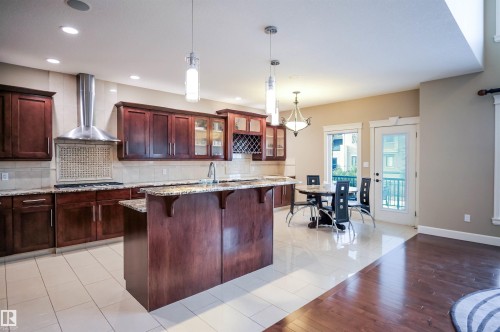 The kitchen features dark wood cabinetry, granite countertops, and a tiled backsplash - 4016 Mactaggart Drive, Edmonton, AB - Indoor Photo Showing Kitchen