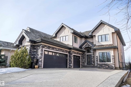 The property features a multi-story exterior with light-colored stucco and dark stone accents - 4016 Mactaggart Drive, Edmonton, AB - Outdoor With Facade