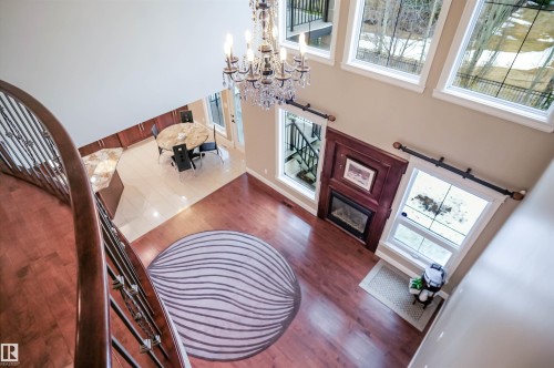Foyer and living area featuring hardwood flooring, a fireplace with a decorative wooden mantel, and a chandelier - 4016 Mactaggart Drive, Edmonton, AB - Indoor Photo Showing Other Room