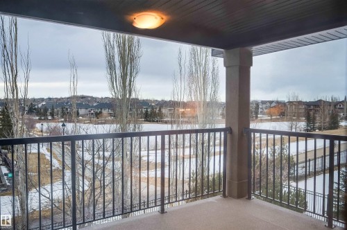 The property features a balcony with a wrought iron railing, offering views of a body of water and distant houses - 4016 Mactaggart Drive, Edmonton, AB -  With Balcony