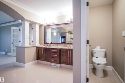 This bathroom features a double vanity with a granite countertop, a large framed mirror, and tile flooring - 4016 Mactaggart Drive, Edmonton, AB - Indoor Photo Showing Bathroom