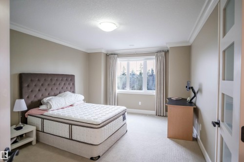 This bedroom features light neutral walls, crown molding, and a carpeted floor - 4016 Mactaggart Drive, Edmonton, AB - Indoor Photo Showing Bedroom
