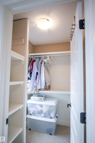 The property features a built-in wardrobe with shelving for organization and a wall-mounted light fixture - 4016 Mactaggart Drive, Edmonton, AB - Indoor With Storage