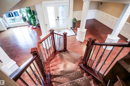Grand entry with rich hardwood flooring, a staircase featuring a decorative wrought iron railing, and wainscoting detailing - 4016 Mactaggart Drive, Edmonton, AB - Indoor Photo Showing Other Room