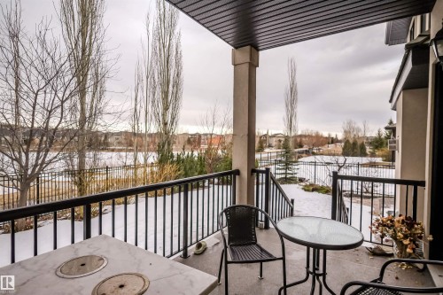 The property features a covered patio area with a concrete floor, offering views of a fenced yard and a body of water - 4016 Mactaggart Drive, Edmonton, AB - Outdoor With Balcony With Exterior