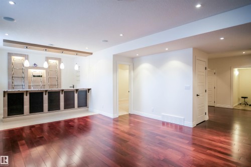 This spacious room features rich hardwood flooring and a built-in bar area - 4016 Mactaggart Drive, Edmonton, AB - Indoor Photo Showing Other Room