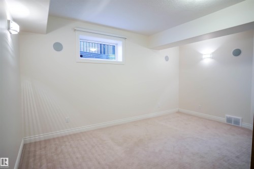Room featuring wall-mounted lighting fixtures, an exterior window, and carpeting - 4016 Mactaggart Drive, Edmonton, AB - Indoor Photo Showing Other Room