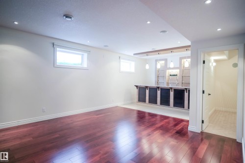 This spacious room features hardwood flooring, recessed lighting, and a well-appointed wet bar with pendant lighting - 4016 Mactaggart Drive, Edmonton, AB - Indoor