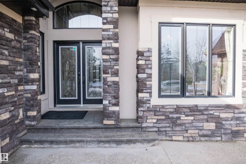 The property features an entrance with double doors, an arched transom window, and stone accents - 4016 Mactaggart Drive, Edmonton, AB - Outdoor