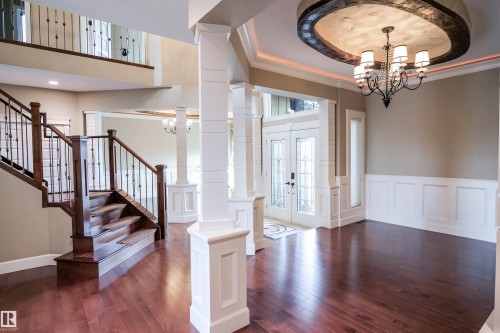 The property features rich hardwood floors, an elegant chandelier with a decorative ceiling medallion, and wainscoting along the walls - 4016 Mactaggart Drive, Edmonton, AB - Indoor Photo Showing Other Room