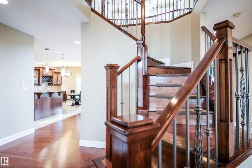 The property features a grand staircase with dark wood railings and decorative metal balusters - 4016 Mactaggart Drive, Edmonton, AB - Indoor Photo Showing Other Room
