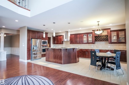 The property features an open-concept kitchen with dark wood cabinetry, stainless steel appliances, and a central island - 4016 Mactaggart Drive, Edmonton, AB - Indoor Photo Showing Kitchen With Upgraded Kitchen