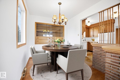 Dining area featuring a decorative chandelier, a built-in wooden display cabinet, and a window providing natural light - 6503 106A Avenue, Edmonton, AB - Indoor Photo Showing Dining Room