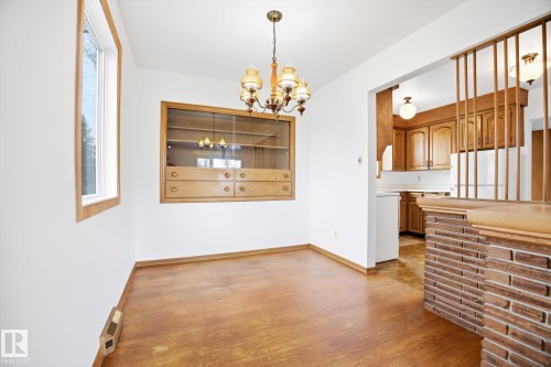 This room features hardwood flooring, a window with wood trim, and a built-in wooden display cabinet with glass doors and drawers - 6503 106A Avenue, Edmonton, AB - Indoor Photo Showing Other Room