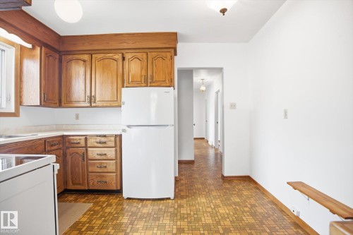 The kitchen features wood cabinetry, a white refrigerator, and a white countertop - 6503 106A Avenue, Edmonton, AB - Indoor Photo Showing Kitchen