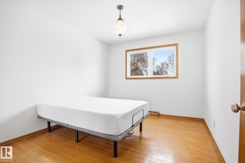 This room features hardwood floors, a window with a wooden frame, and a decorative ceiling light fixture - 6503 106A Avenue, Edmonton, AB - Indoor