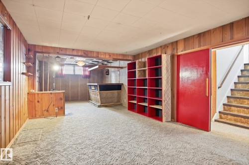 This expansive lower level offers a large open space with wood paneling and a patterned carpet - 6503 106A Avenue, Edmonton, AB - Indoor Photo Showing Other Room