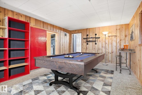 Recreational room featuring wood paneling, a patterned area rug, and a red sliding door - 6503 106A Avenue, Edmonton, AB - Indoor Photo Showing Other Room