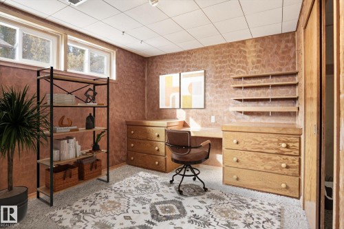 This versatile room features warm-toned walls, built-in wooden cabinetry with drawers, and a built-in wooden desk area - 6503 106A Avenue, Edmonton, AB - Indoor Photo Showing Other Room