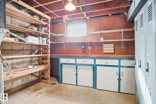 This room features exposed ceiling joists, concrete flooring, and built-in wooden shelving for storage - 6503 106A Avenue, Edmonton, AB - Indoor