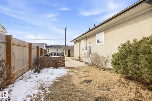The property features a stucco exterior, a wooden fence, and a concrete pathway - 6503 106A Avenue, Edmonton, AB - Outdoor