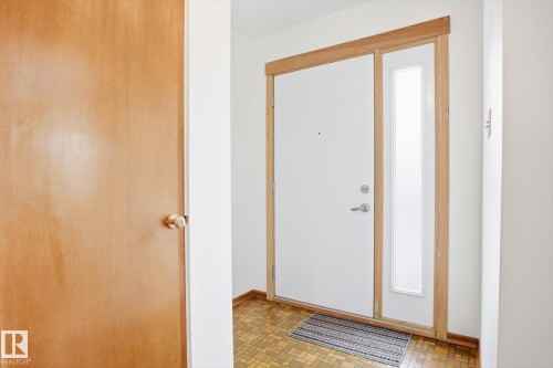 Entryway featuring a white door with a side light and natural wood trim, set against white walls - 6503 106A Avenue, Edmonton, AB - Indoor Photo Showing Other Room