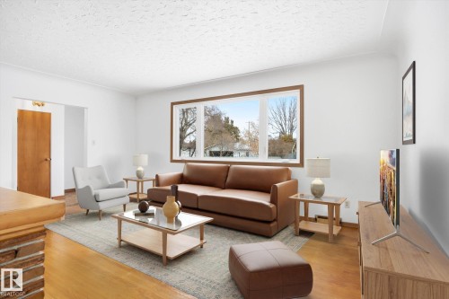 Living room featuring hardwood floors, a large window with wood trim, and white painted walls - 6503 106A Avenue, Edmonton, AB - Indoor Photo Showing Living Room