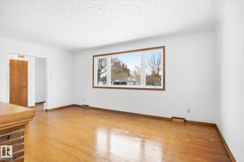 The interior features wood flooring, white walls, and a large window with wooden trim - 6503 106A Avenue, Edmonton, AB - Indoor