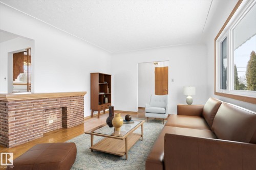 Living area featuring hardwood floors, a brick fireplace with a wood mantle, and a large window providing ample natural light - 6503 106A Avenue, Edmonton, AB - Indoor Photo Showing Living Room With Fireplace