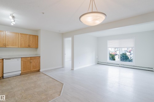 Open concept living space featuring light wood cabinetry, a white dishwasher, and light-colored flooring - 113 309 Clareview Station Drive, Edmonton, AB - Indoor Photo Showing Kitchen