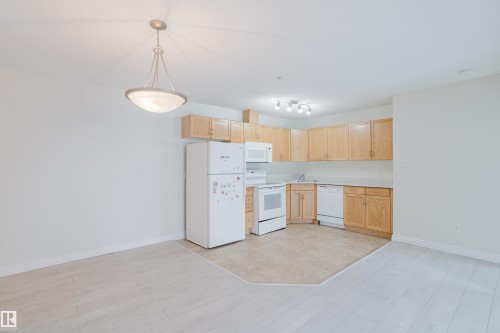 The property features a kitchen with light wood cabinetry, white appliances, and a tiled floor area - 113 309 Clareview Station Drive, Edmonton, AB - Indoor Photo Showing Kitchen