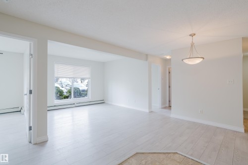 This bright interior space features light-toned flooring, a window with a roller shade, and a ceiling light fixture - 113 309 Clareview Station Drive, Edmonton, AB - Indoor