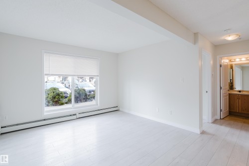 The property features a bright room with light-toned flooring, a large window, and white walls - 113 309 Clareview Station Drive, Edmonton, AB - Indoor Photo Showing Other Room
