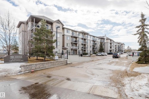 The property features a multi-story apartment building with balconies, a paved drive, and a stone retaining wall - 113 309 Clareview Station Drive, Edmonton, AB - Outdoor