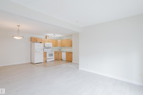 The property features a kitchen area with light wood cabinetry, white appliances including a refrigerator, range, and microwave, and a tiled floor - 113 309 Clareview Station Drive, Edmonton, AB - Indoor Photo Showing Kitchen